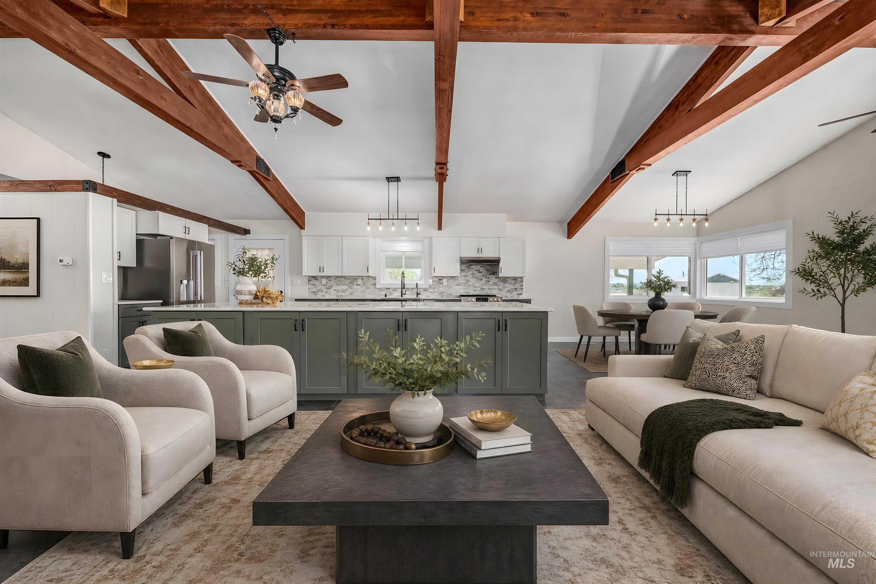 748 Pringle Road Weiser, ID 83672 - Photo 6 of 47 Open-concept living space featuring vaulted ceilings with exposed wood beams, a contemporary kitchen island with a light-toned countertop, stainless steel appliances, and a dining area with multiple windows