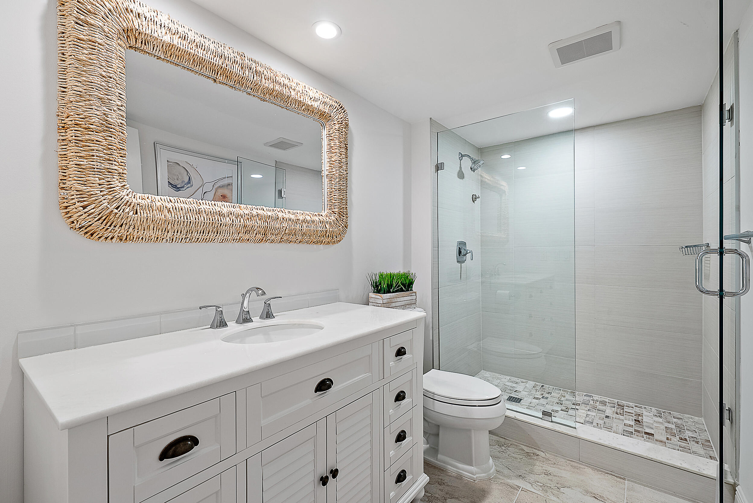 16647 Traders Crossing North, Unit 126 Jupiter, FL 33477 - Photo 27 of 45 a bathroom with a toilet a sink a mirror and a shower