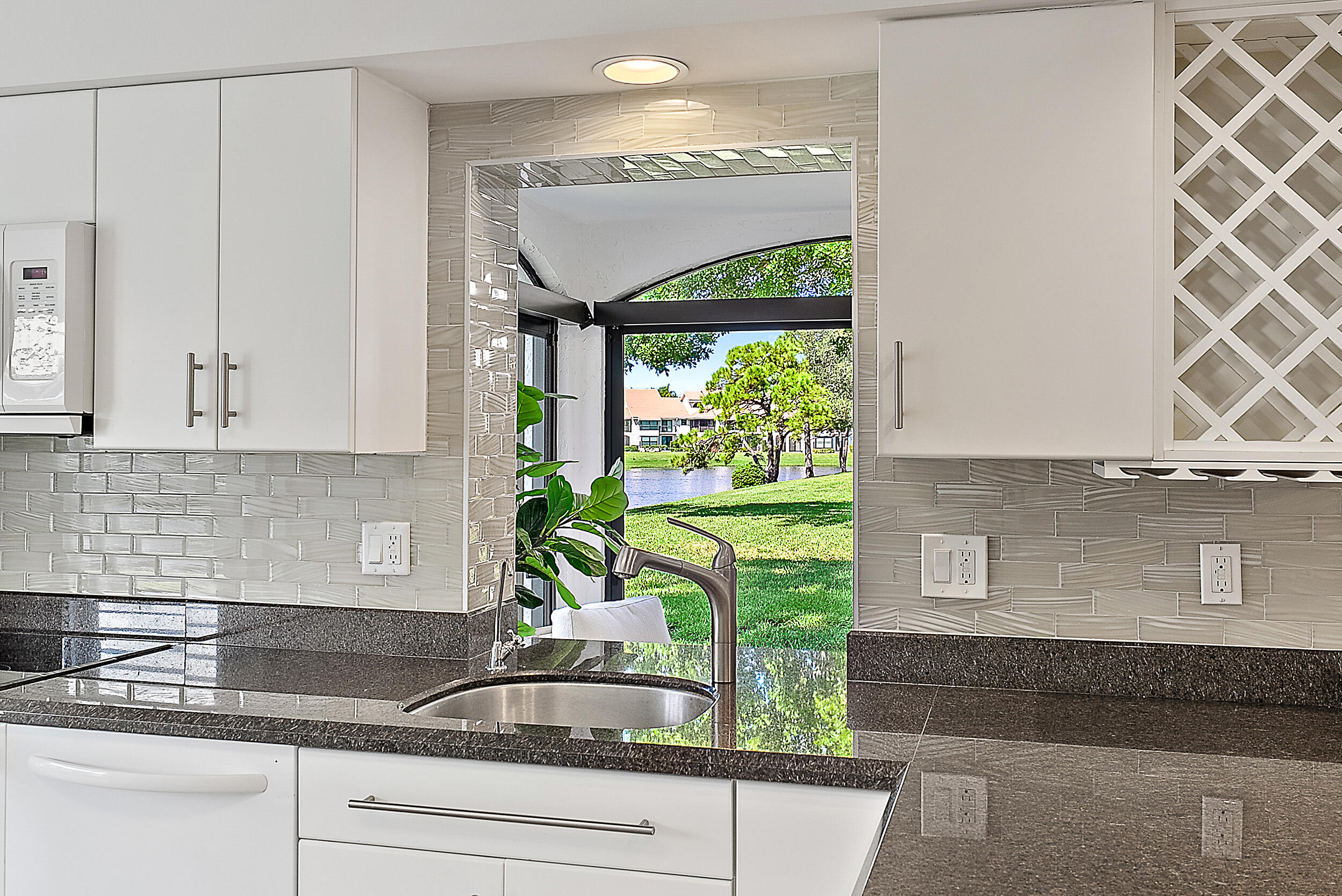 16647 Traders Crossing North, Unit 126 Jupiter, FL 33477 - Photo 7 of 45 a kitchen with stainless steel appliances granite countertop a potted plant on the granite counter tops and a window