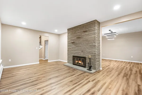 a view of an empty room with wooden floor fireplace and a window