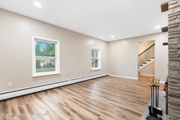 a view of an empty room with wooden floor and a window
