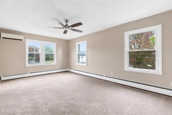 an empty room with windows and ceiling fan