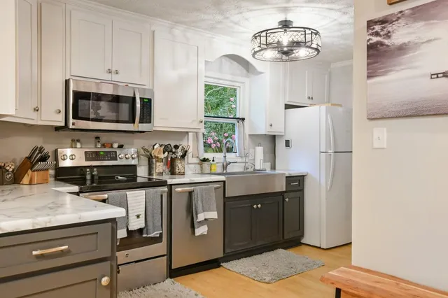 a kitchen with stainless steel appliances granite countertop a refrigerator a stove a sink dishwasher and a refrigerator with wooden floor