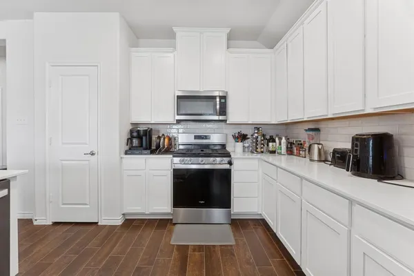 a kitchen with granite countertop a stove top oven a sink dishwasher and a refrigerator with wooden floor