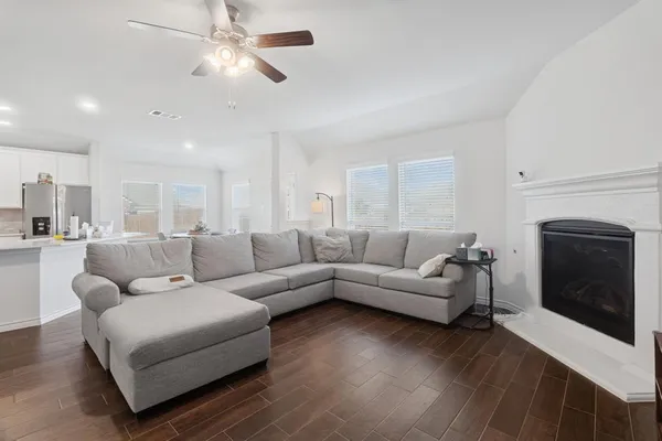 a living room with furniture a fireplace and a ceiling fan