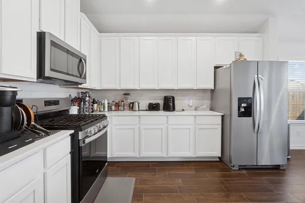 a kitchen with stainless steel appliances granite countertop a refrigerator stove a sink and dishwasher with wooden floor