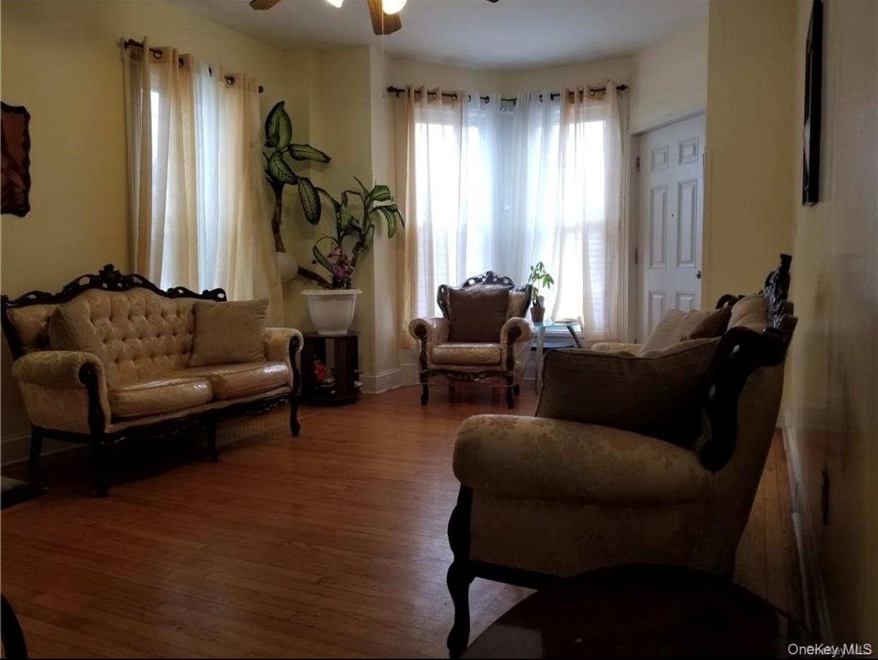 7 Clinton Street Haverstraw, NY 10927 - Photo 11 of 20 Living area featuring wood-finish flooring, a bay window with multiple panels, and a ceiling fan with integrated lighting