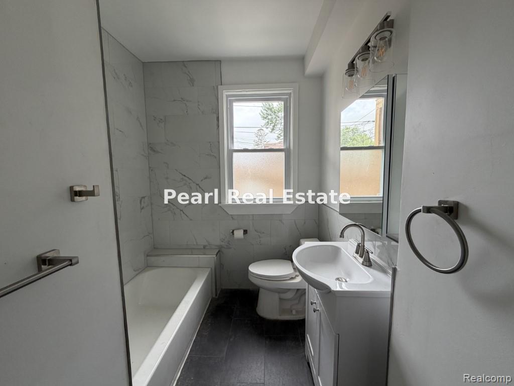2s Santa Rosa Drive Detroit, MI 48221 - Photo 12 of 16 Full bathroom featuring a white porcelain tub, a vanity with an integrated sink and brushed nickel faucet, a wall-mounted mirror, and overhead lighting