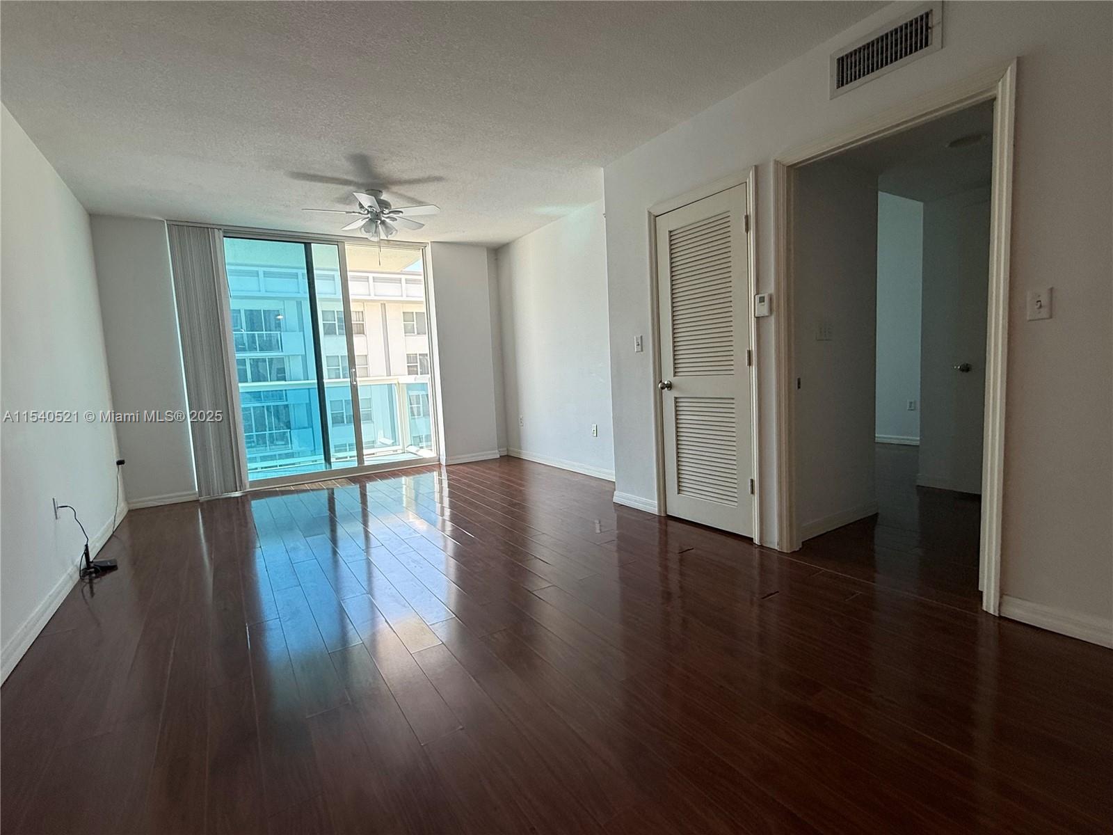 9201 Collins Avenue, Unit 1023 Surfside, FL 33154 - Photo 3 of 28 an empty room with wooden floor and windows