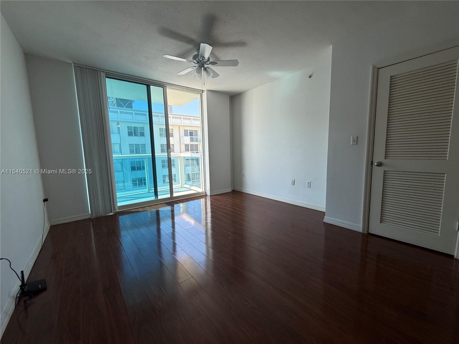 9201 Collins Avenue, Unit 1023 Surfside, FL 33154 - Photo 4 of 28 a view of an empty room with wooden floor and a window