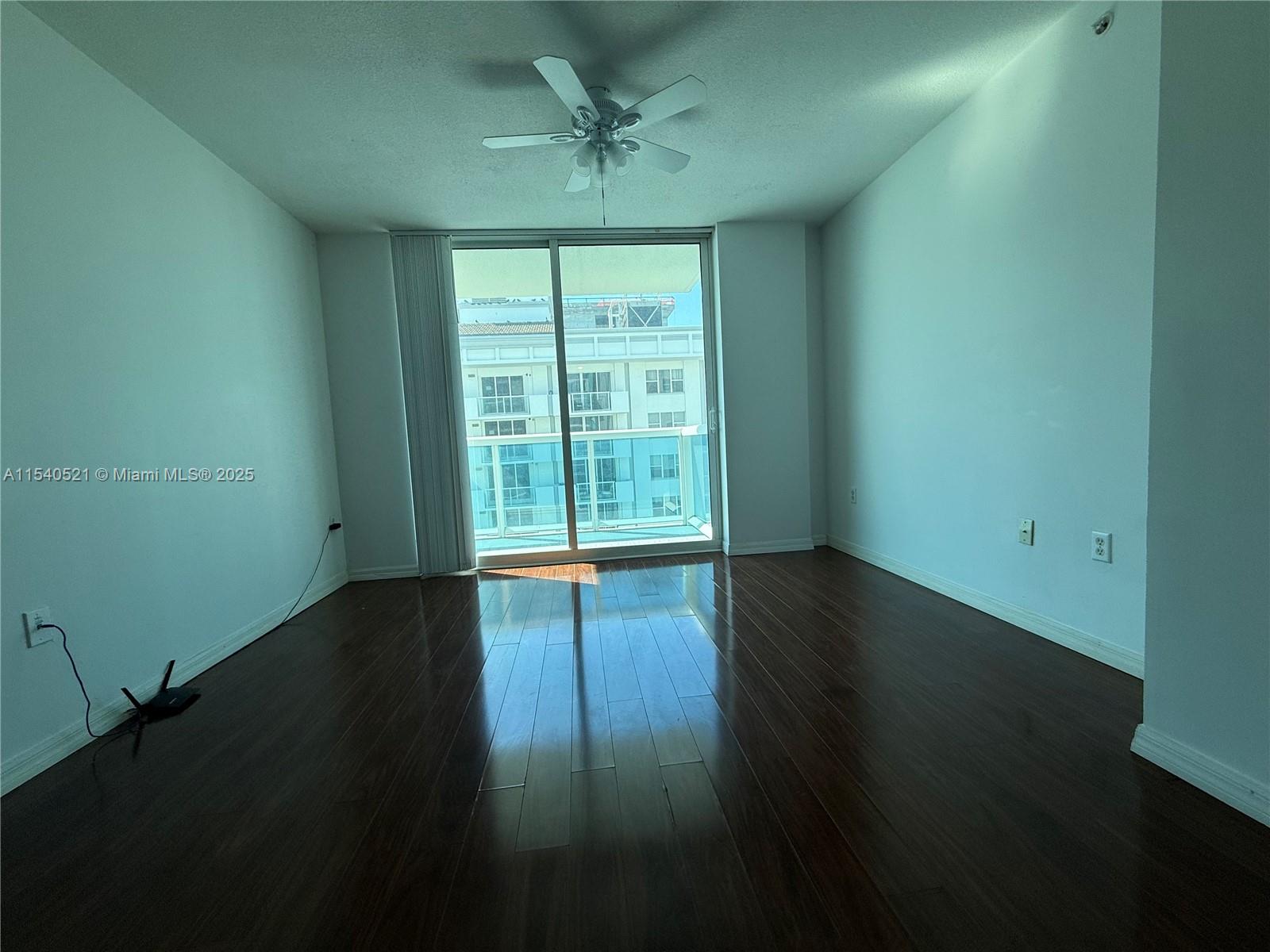 9201 Collins Avenue, Unit 1023 Surfside, FL 33154 - Photo 6 of 28 a view of an empty room with wooden floor and a window