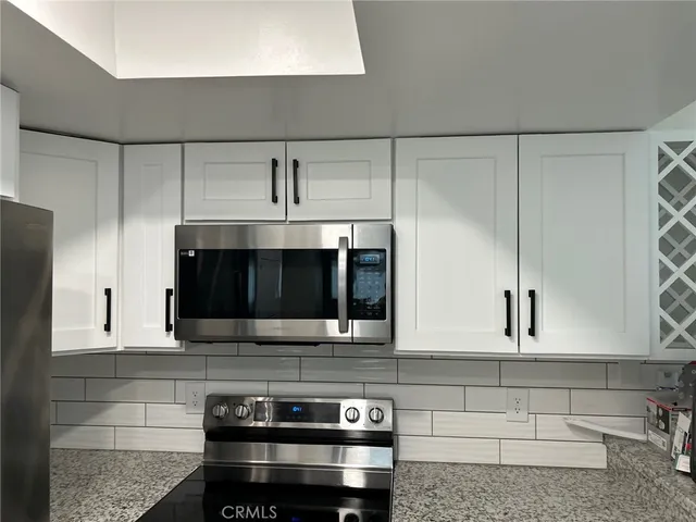 a kitchen with stainless steel appliances kitchen island granite countertop a stove and a microwave