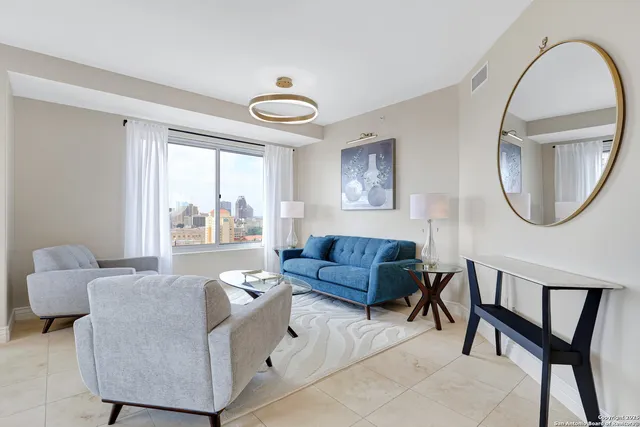 a living room with couches a dining table a chandelier with wooden floor and couches