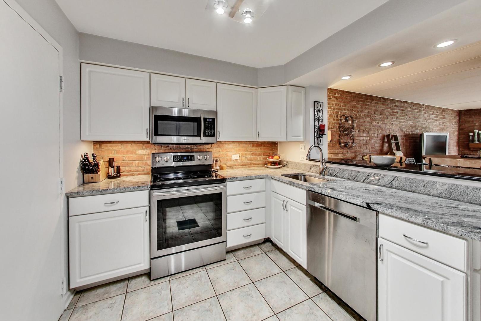 651 West Sheridan Road, Unit 7C Chicago, IL 60613 - Photo 10 of 27 a kitchen with stainless steel appliances granite countertop a stove a sink and a microwave