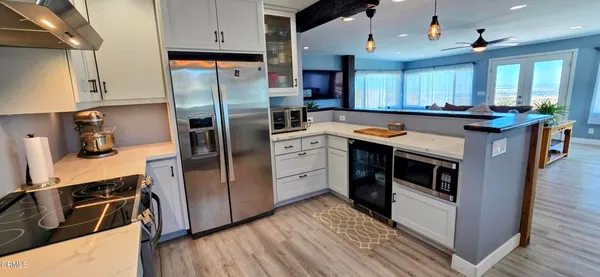 a kitchen with stainless steel appliances kitchen island granite countertop a refrigerator a sink dishwasher a stove and white countertops with wooden floor