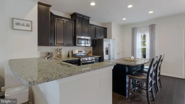 a kitchen with granite countertop a sink chairs and cabinets