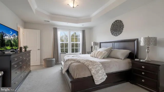 a bedroom with a bed and a flat tv screen on dresser
