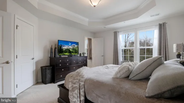 a bedroom with a bed and a flat tv screen on dresser