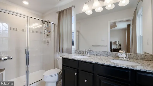 a bathroom with a granite countertop sink mirror toilet and shower