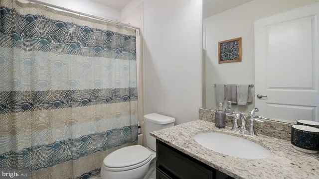 a bathroom with a granite countertop sink mirror vanity and toilet