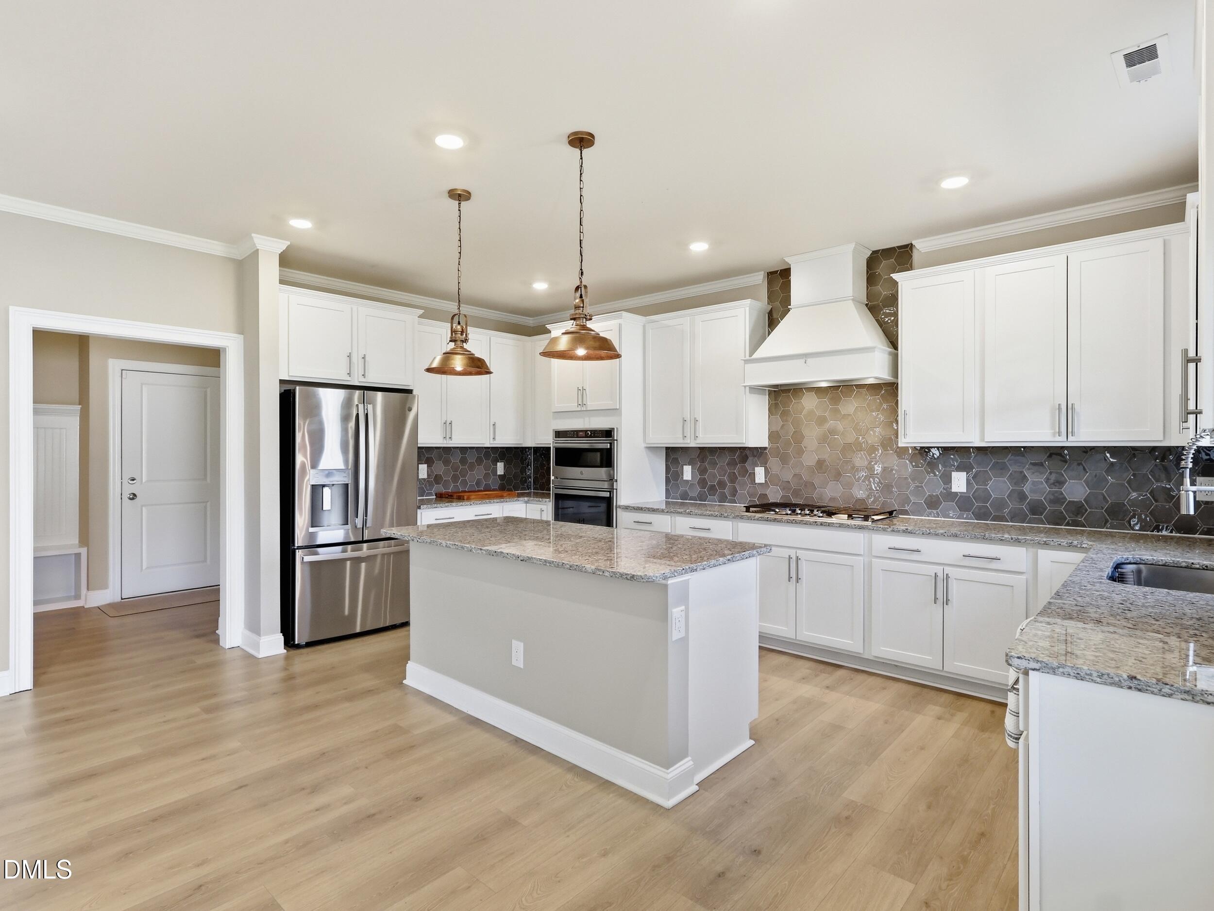 2709 Womble Ridge Drive New Hill, NC 27562 - Photo 19 of 60 a large kitchen with stainless steel appliances kitchen island granite countertop a refrigerator a stove a sink and a wooden floors