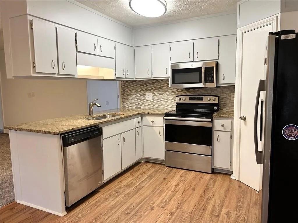 5490 Marbut Road Lithonia, GA 30058 - Photo 12 of 19 a kitchen with granite countertop a sink stainless steel appliances and white cabinets