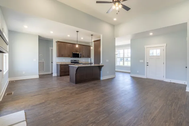 an open kitchen with refrigerator and wooden floor