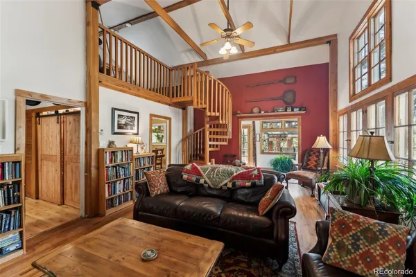 a living room with furniture a bookshelf and kitchen view