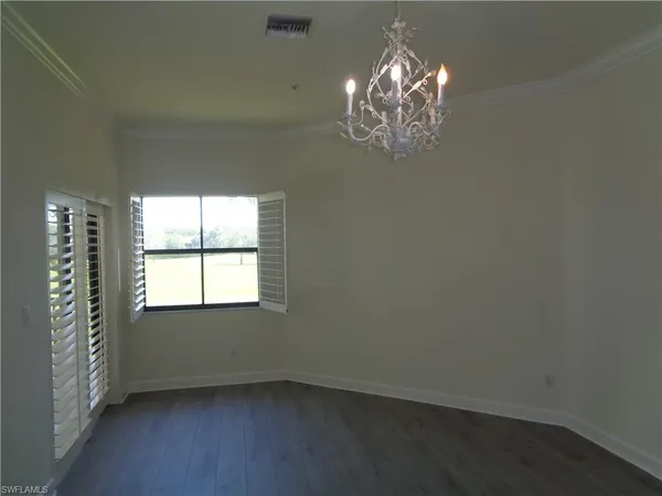 en empty room with windows and chandelier