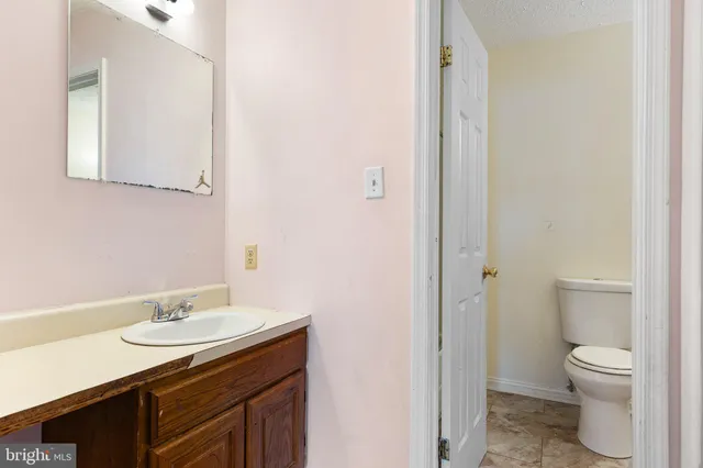 a bathroom with a granite countertop sink toilet and a mirror