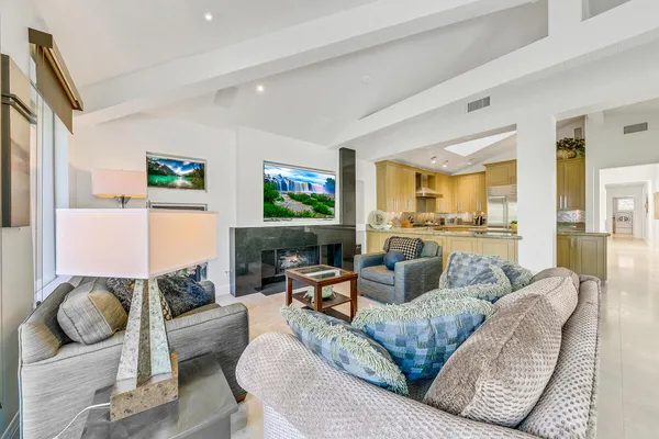a living room with furniture kitchen view and a large window