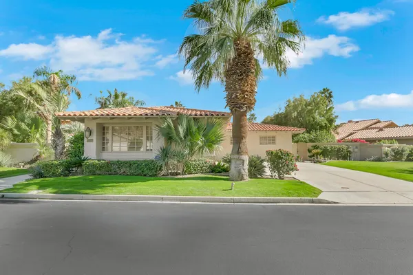 a view of a house with a yard and palm trees