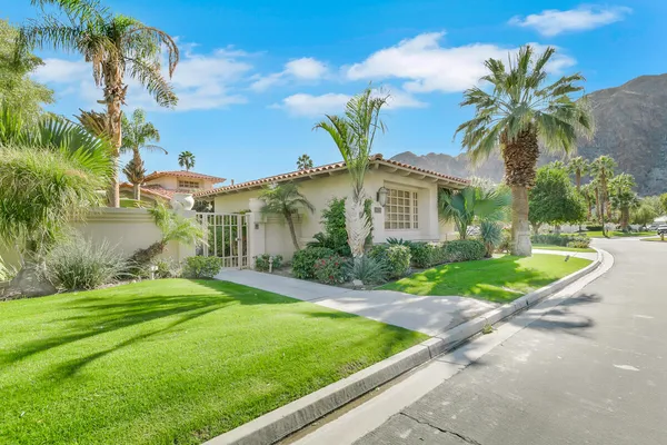 a view of a house with a yard and palm trees