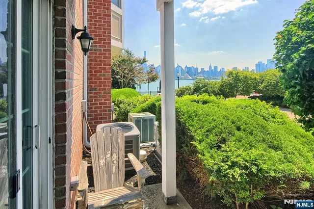 a front view of a residential apartment building with a yard and potted plants