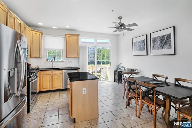 a kitchen with stainless steel appliances kitchen island granite countertop a table chairs and a refrigerator