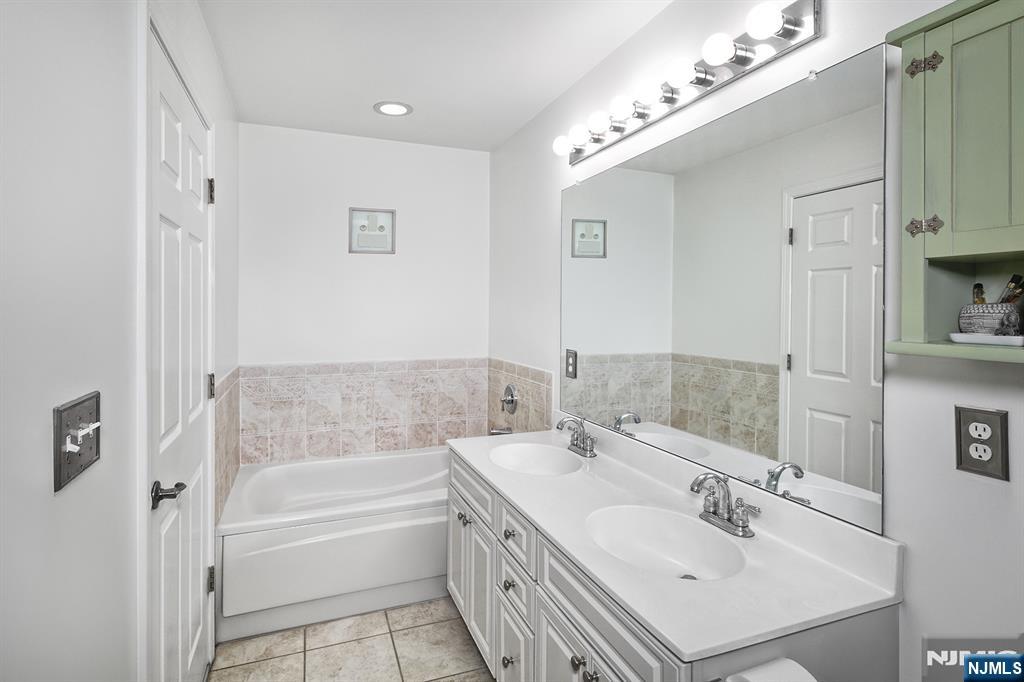 406 Newburgh Court West New York, NJ 07093 - Photo 9 of 31 a bathroom with a double vanity sink a mirror and a bathtub