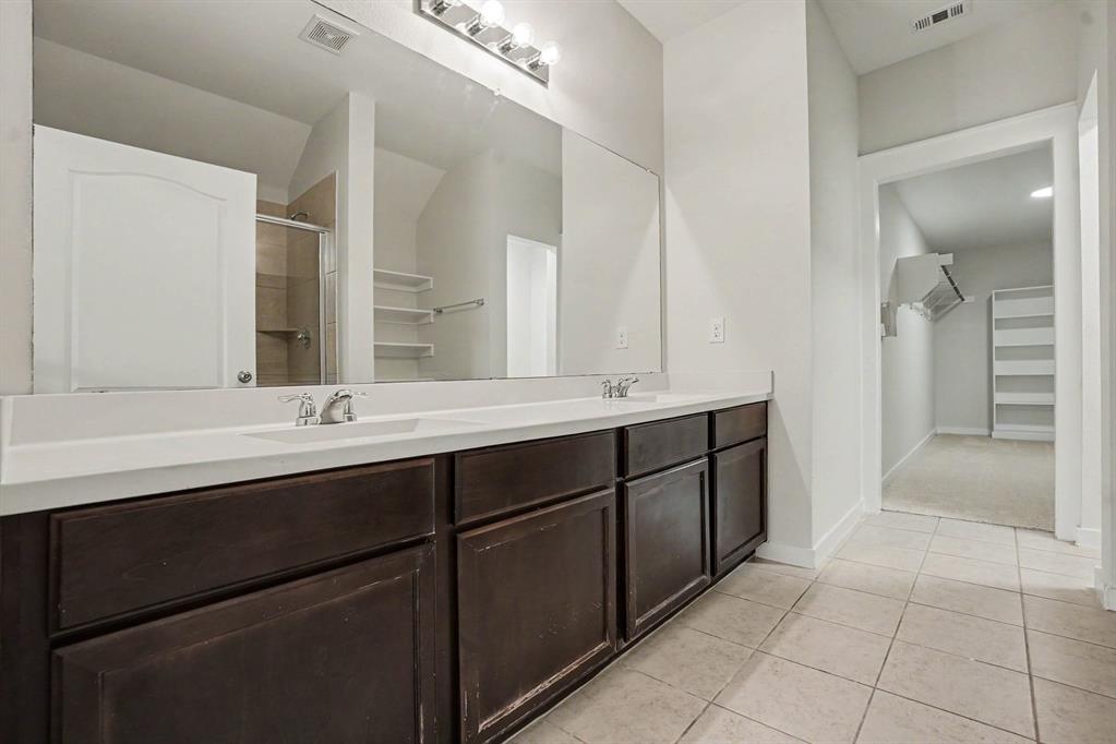 2606 Middleton Road Glenn Heights, TX 75154 - Photo 13 of 18 Master- Dual vanity with integrated sinks, expansive mirror, dark wood-finish cabinetry, and tiled flooring