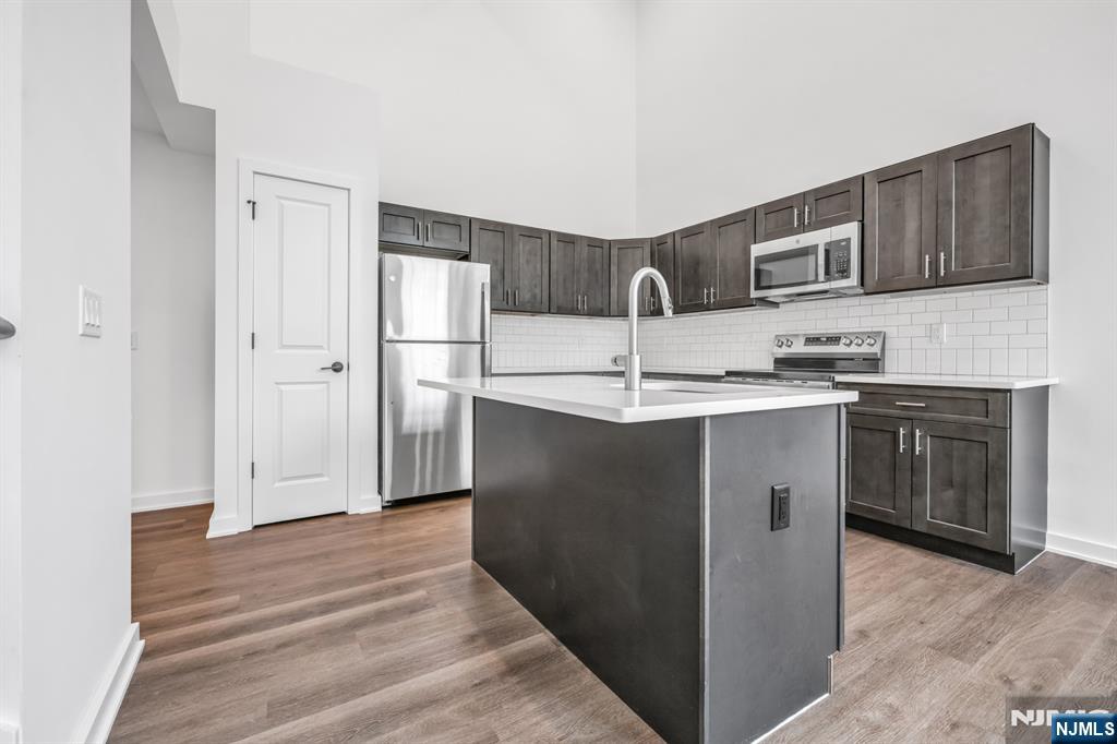 315 Railroad Avenue, Unit 107 East Rutherford, NJ 07073 - Photo 8 of 25 a kitchen with stainless steel appliances granite countertop a sink a stove a refrigerator and cabinets