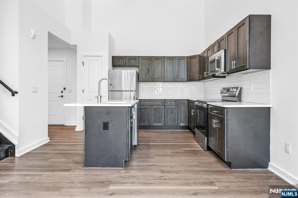 315 Railroad Avenue, Unit 107 East Rutherford, NJ 07073 - Photo 9 of 25 a kitchen with stainless steel appliances granite countertop a stove top oven a sink dishwasher and a refrigerator with wooden floor