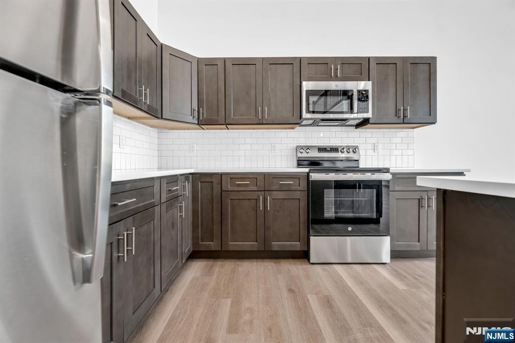 315 Railroad Avenue, Unit 107 East Rutherford, NJ 07073 - Photo 10 of 25 a kitchen with stainless steel appliances granite countertop a stove top oven a sink and dishwasher