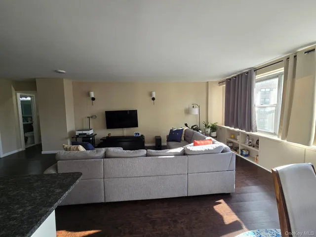 a living room with furniture kitchen view and a wooden floor