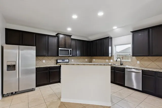 a kitchen with stainless steel appliances granite countertop a sink a stove a refrigerator and cabinets