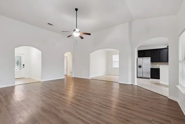 a view of an empty room with window and wooden floor