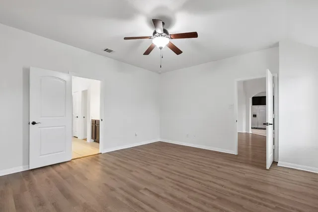 a view of empty room with wooden floor and ceiling fan