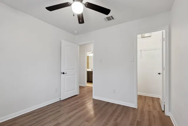 an empty room with wooden floor and ceiling fan