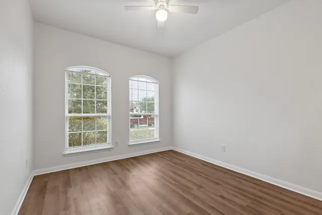 an empty room with wooden floor and windows
