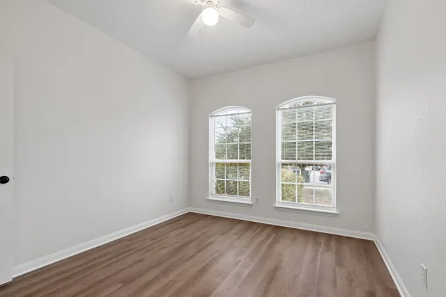 an empty room with wooden floor and windows