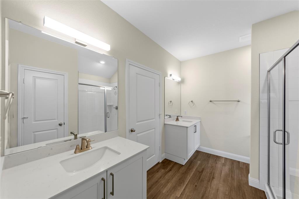 200 Pennington Road Josephine, TX 75173 - Photo 15 of 22 Bathroom featuring dual vanities with white cabinetry and integrated sinks, quartz-finish countertops, and wood-finish flooring