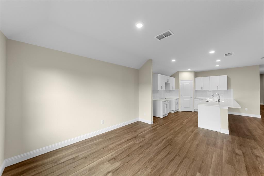 200 Pennington Road Josephine, TX 75173 - Photo 7 of 22 Open-concept living space featuring wood-finish flooring, recessed lighting, and a kitchen with white cabinetry, a kitchen island, and a sink with a gooseneck faucet