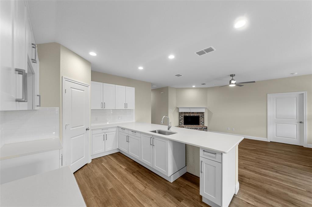 200 Pennington Road Josephine, TX 75173 - Photo 9 of 22 Open-concept kitchen featuring white cabinetry with brushed nickel hardware, white countertops, subway tile backsplash, and wood-finish flooring